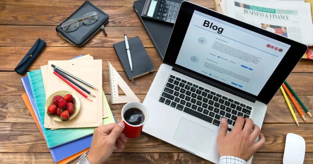 Blog writing workspace with a laptop displaying an article and writing materials.
